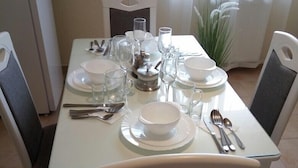Una mesa de comedor dispuesta con platos blancos, tazones, vasos y cubiertos.