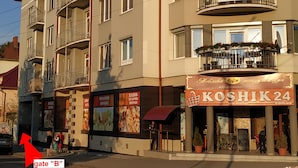 Un edificio de varios pisos con balcones y una tienda con el rótulo "KOSHIK 24".