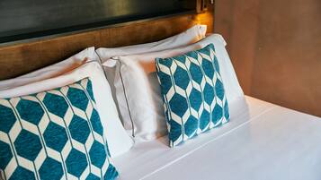 A neatly made bed with white linens and two patterned pillows.