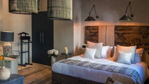 Une chambre à coucher moderne avec un grand lit, des lampes de chevet, une petite table ornée de fleurs et une œuvre d’art accrochée au mur.