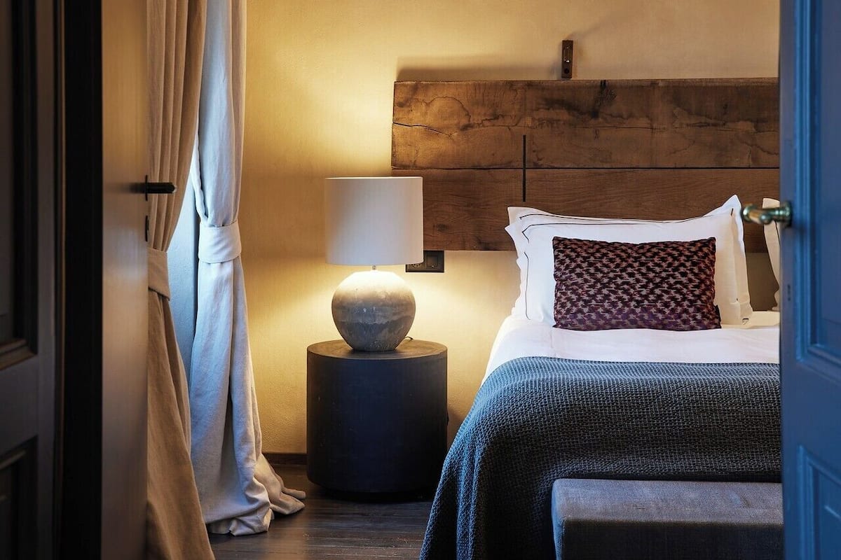 Quarto com cama, abajur, objeto decorativo redondo e cabeceira.