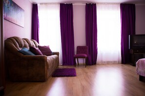 A living room with a brown sofa, a purple armchair, and a wooden floor. - Best Apartments on Kyryla & Mefodia (Mukachevo)