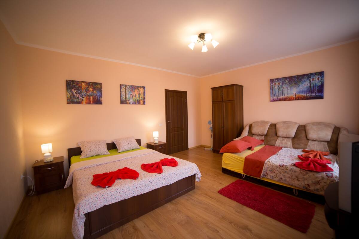 Een slaapkamer met twee bedden, houten vloeren en kunstwerken aan de wanden.