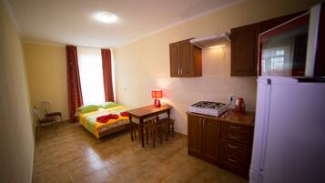 A compact kitchen with a bed, a dining table, and a refrigerator.