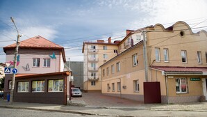 A street view with buildings, a cobblestone road, and a parked car.