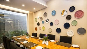 Une salle de conférence avec une longue table préparée pour une réunion, entourée de chaises et décorée de diverses assiettes accrochées au mur.