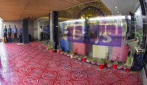 A hotel entrance with a red patterned floor, a large 'Days' sign, and potted plants along the walkway. - The New Days (Dhaka)