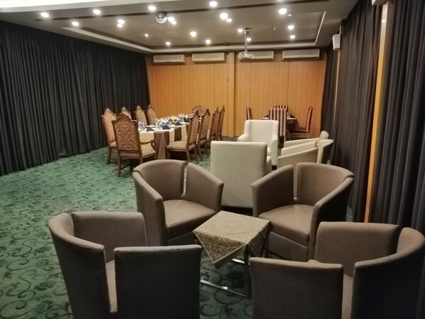 A conference room with a long table, multiple chairs, and a small table with a patterned tablecloth.