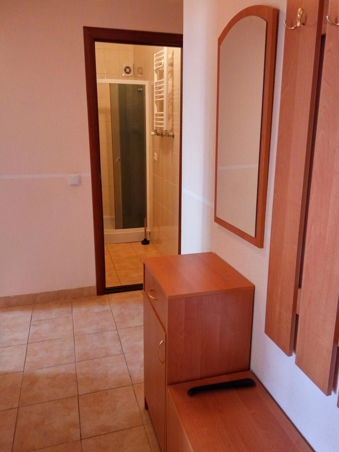 Ein Zimmer mit einem Holzkasten, einem Spiegel und einer Tür zum Badezimmer.