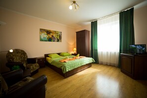 A bedroom with a bed, a chair, a TV, a painting, and a window with curtains. - Best One Room Apartments (Mukachevo)