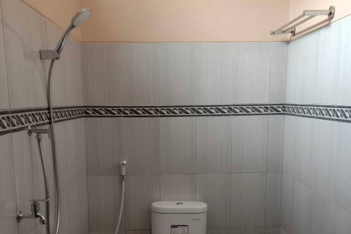 Ett litet badrum med kakel på väggarna, utrustat med toalett, dusch och handduksställ.
