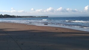 A beach with a clear sky, calm sea, and footprints in the sand. - Rivana Hotel (Cijulang)