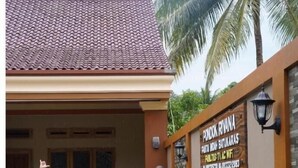 A swimming pool area with a tiled roof and a signboard. - Rivana Hotel (Cijulang)