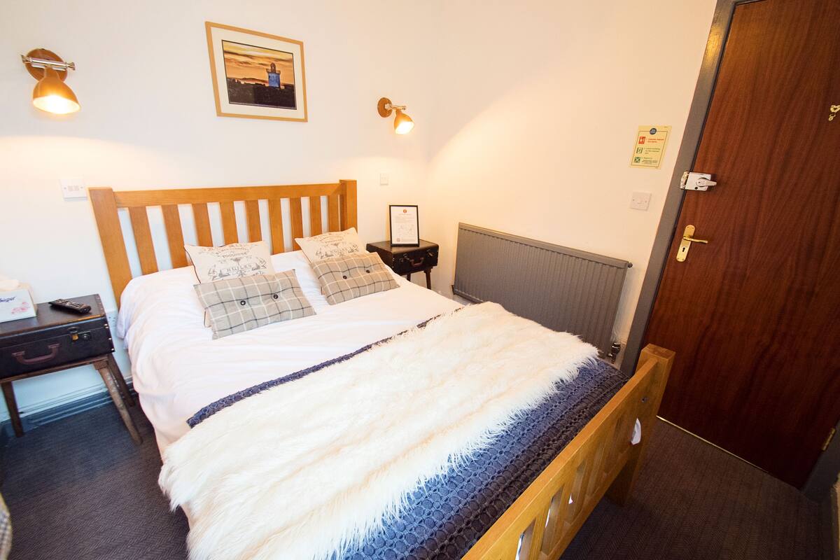 A neatly made bed with a white and blue blanket, a wooden headboard, and two bedside lamps.