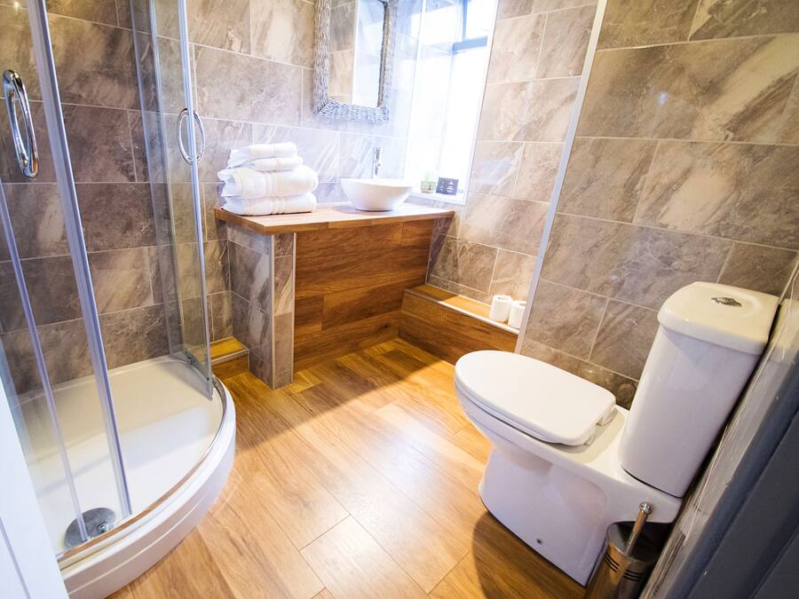 A bathroom with a glass-enclosed shower, a wooden vanity with a sink, and a toilet.