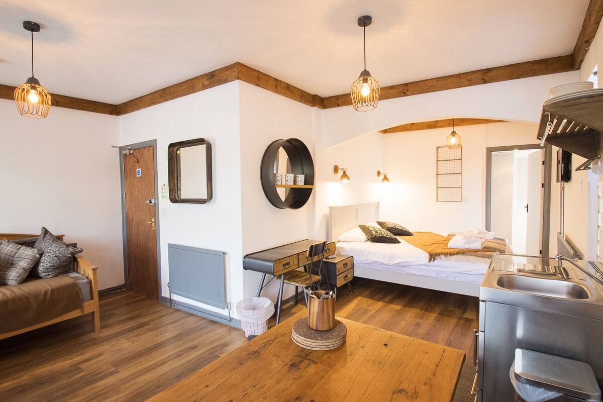 A room with a bed, a desk, a chair, a sink, and a mirror.