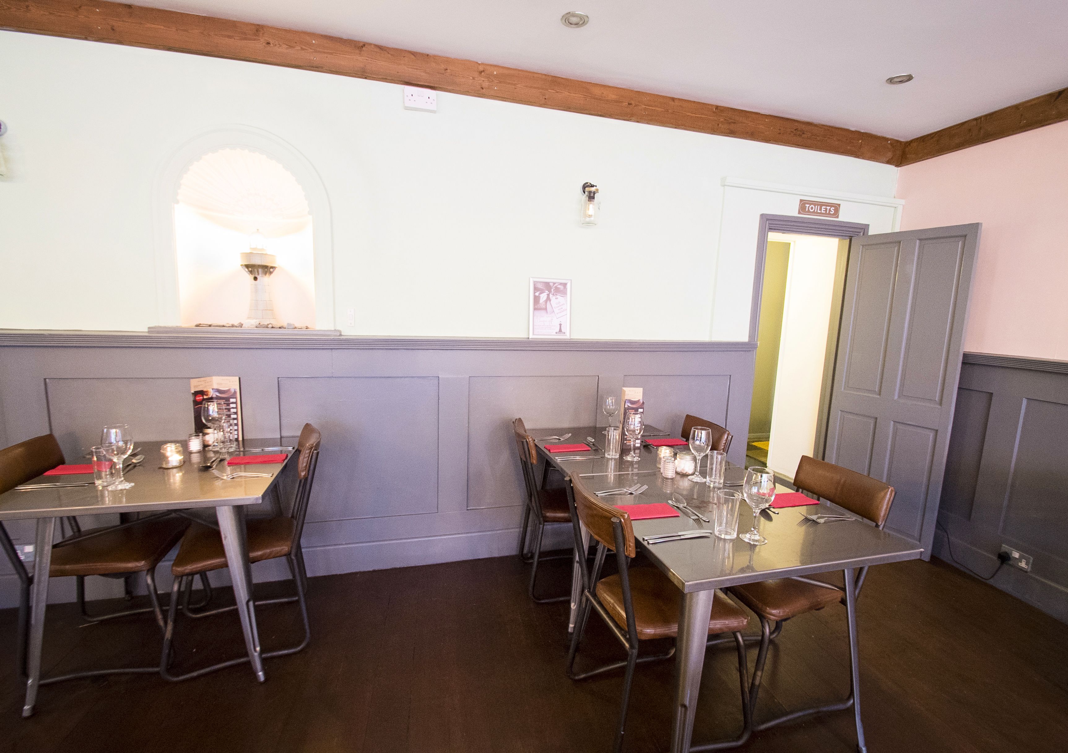 A dining area with tables set for four, each with chairs and tableware.