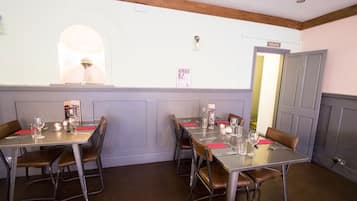 A dining area with tables set for four, each with chairs and tableware.