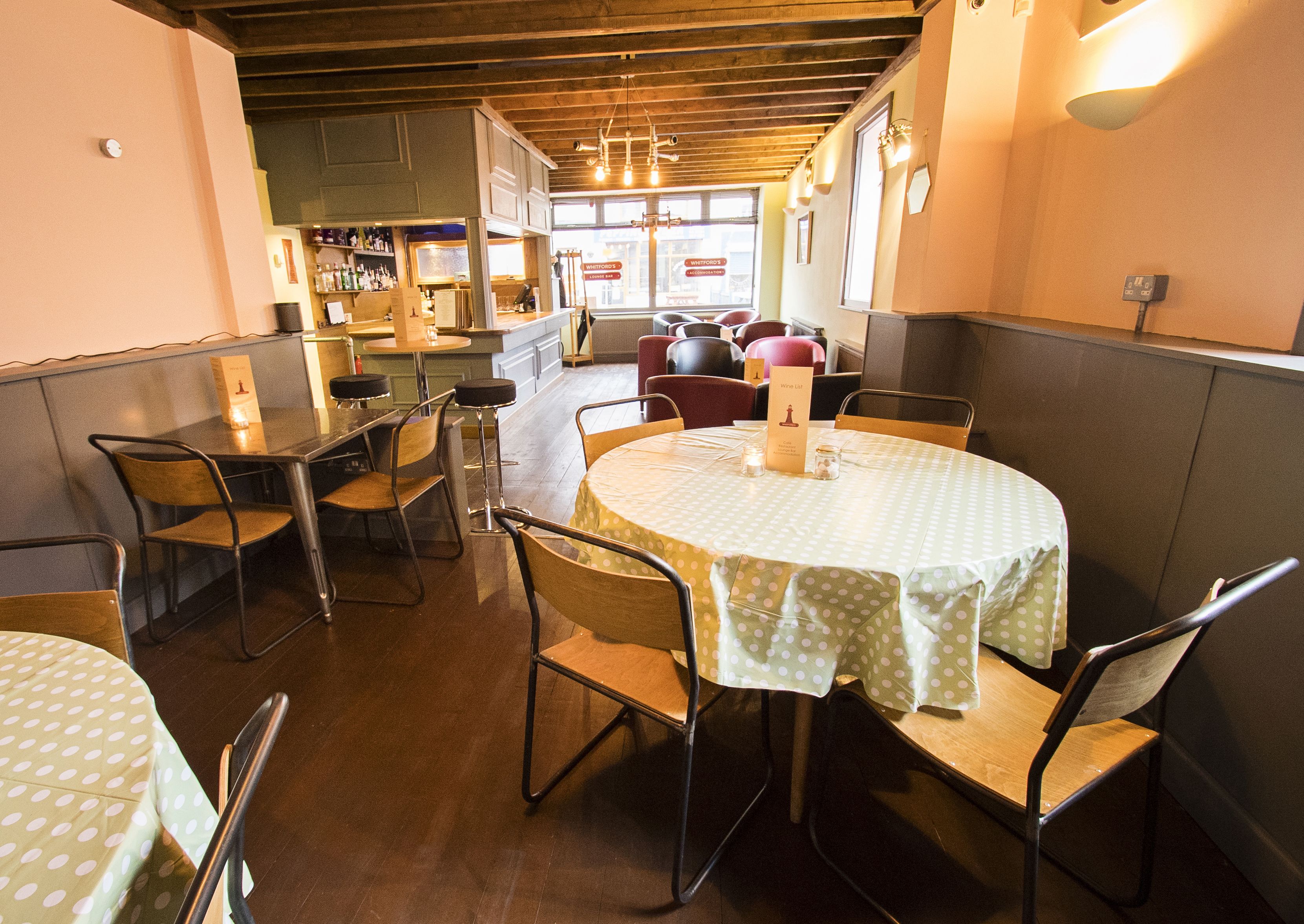 L'intérieur d'un restaurant avec des tables rondes, des chaises et un coin bar.
