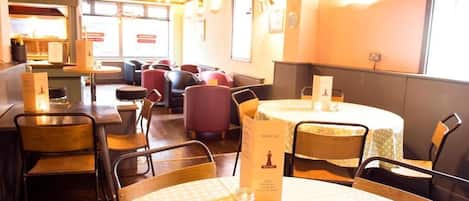 Un restaurant avec des tables rondes, des chaises et un présentoir à menus.
