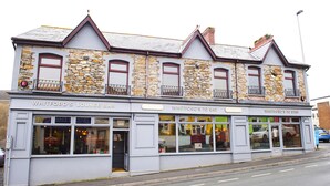 A building with three sections labeled "Whitford's Lounge Bar," "Whitford's to Eat," and "Whitford's to Stay." - Nik The Greek (Burry Port)
