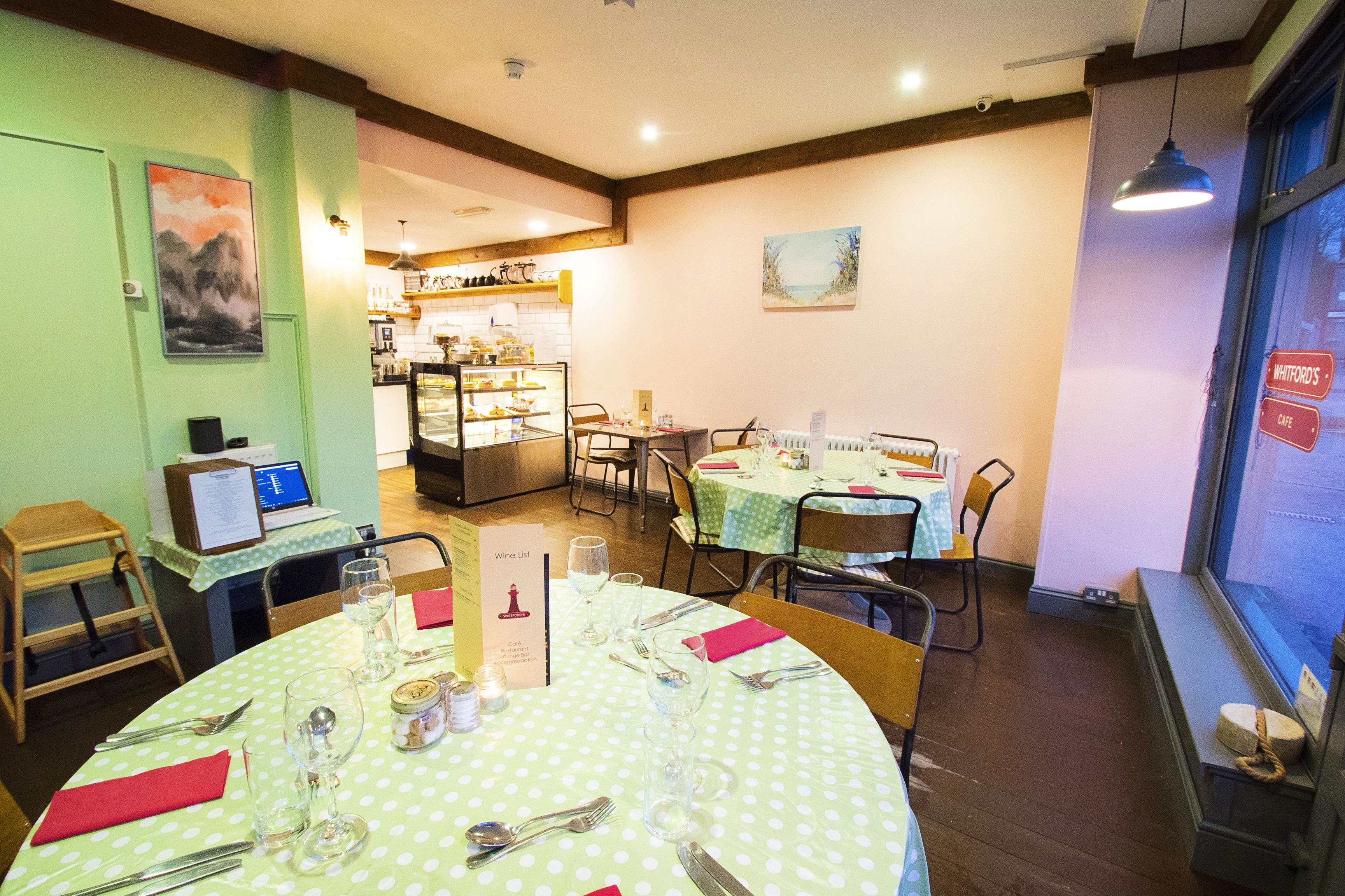 A restaurant interior with round tables, chairs, and a menu stand.