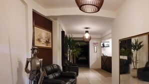 Un salon spacieux avec un canapé en cuir noir, un grand miroir qui reflète la pièce et une sculpture métallique décorative.