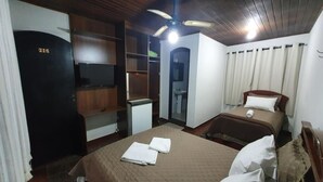 Une chambre avec un lit, un bureau, une armoire et un ventilateur de plafond.