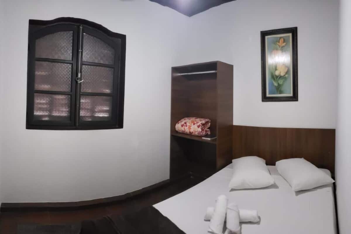 Une chambre à coucher avec un lit, une armoire, une fenêtre et un tableau encadré au mur.