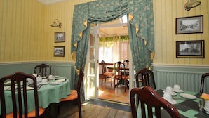 A dining room with a table set for four, chairs, and a window with curtains. - Edderton Hall Country House (Welshpool)