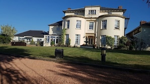 A large, two-story house with a curved facade, multiple windows, and a well-maintained lawn. - Edderton Hall Country House (Welshpool)