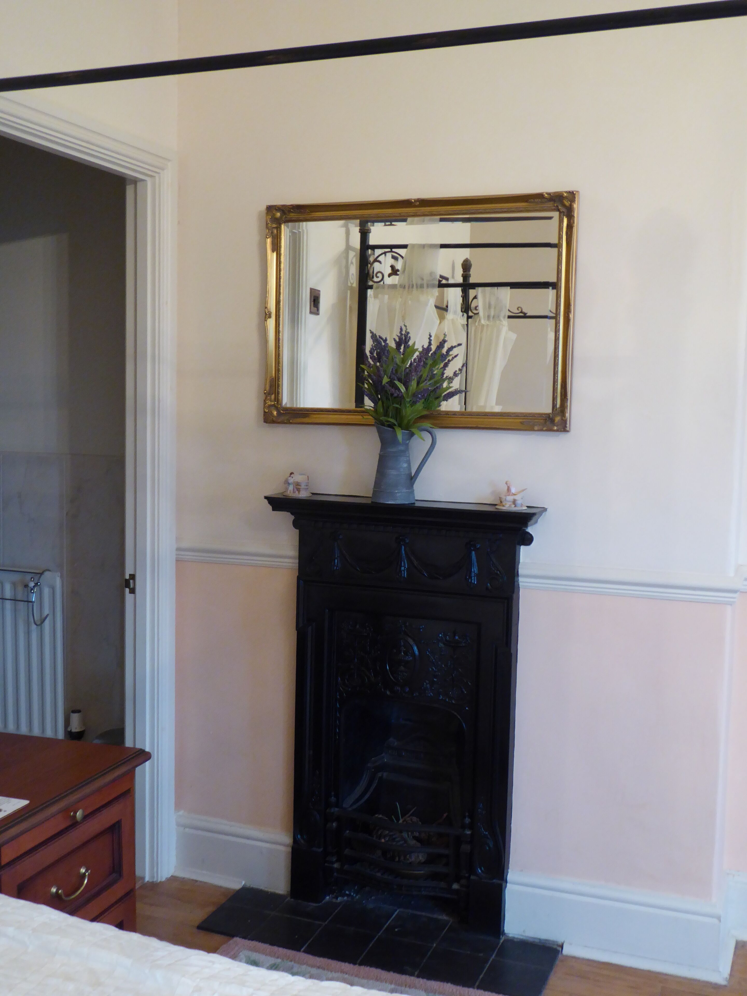 Een kamer met een open haard, een spiegel en een vaas met bloemen.