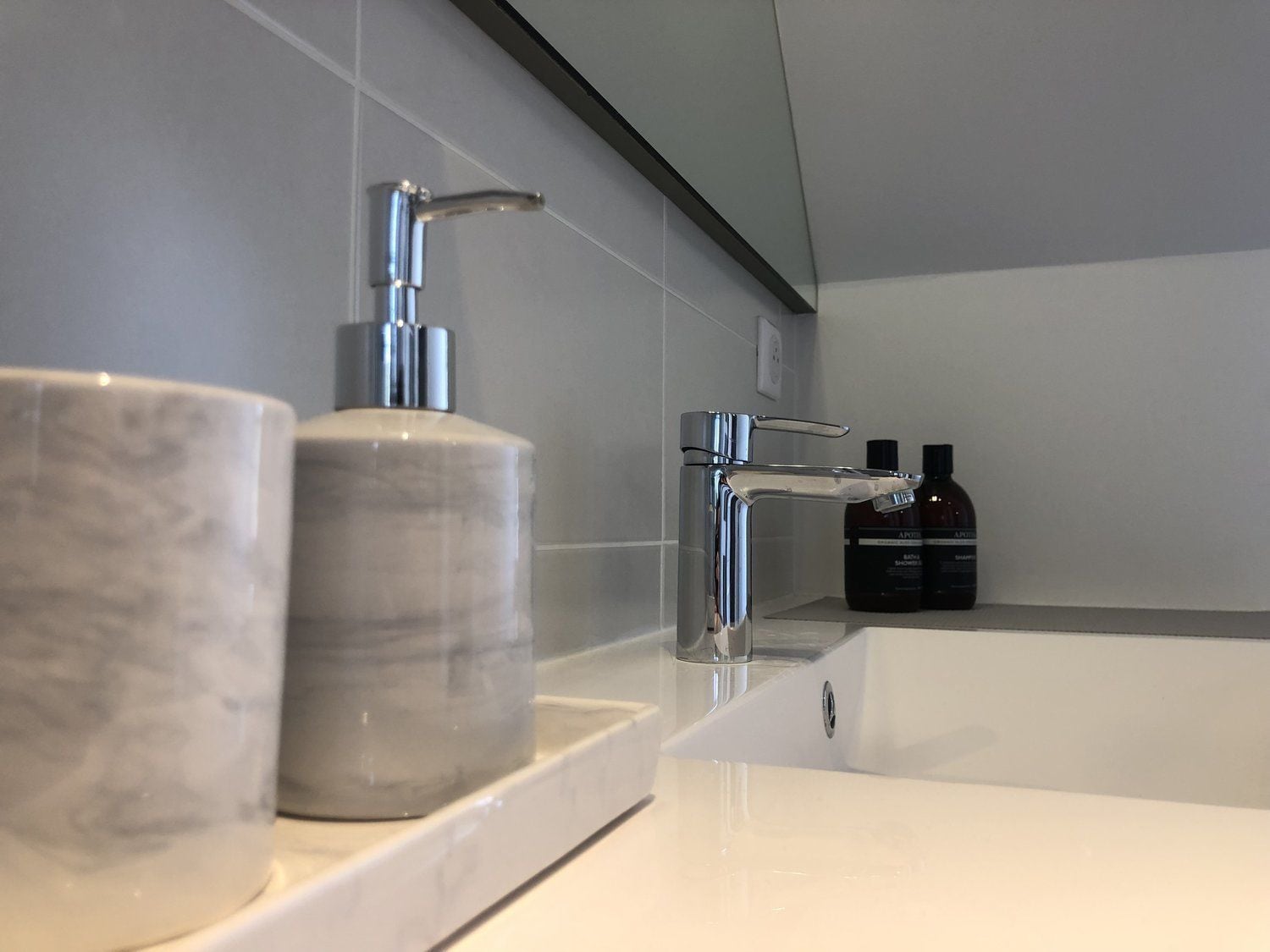 Ein modernes Badezimmer mit einem Marmorwaschbecken, einem chromfarbenen Wasserhahn und einer großen Badewanne.