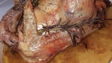 A roasted chicken in a white dish with a golden-brown sauce.