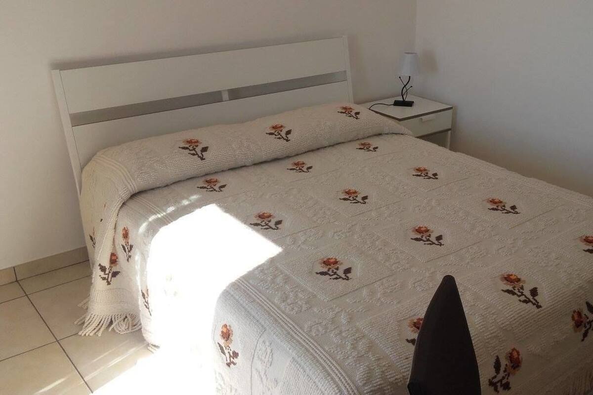 Un lit avec une couvre-lit à motifs floraux et une table de chevet avec une lampe.