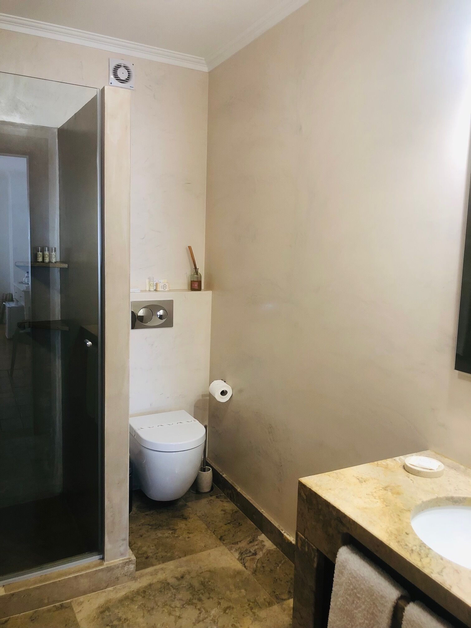 A bathroom with a toilet, a sink, a shower, and a mirror.