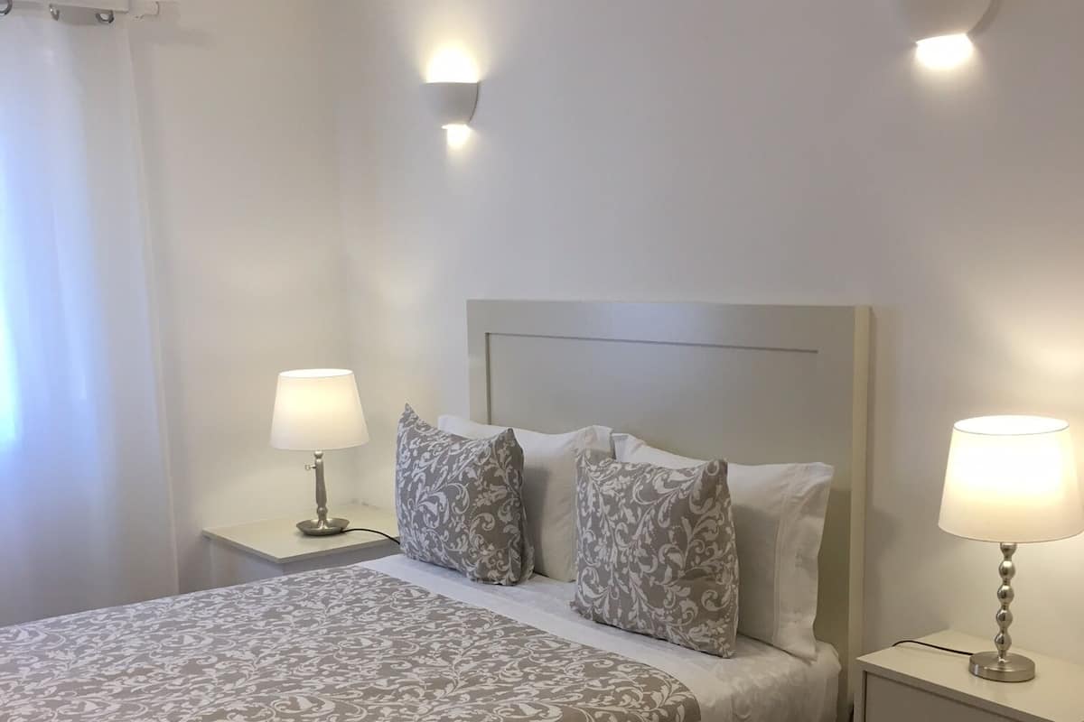 A neatly made bed with patterned bedding, two bedside lamps, and a headboard.