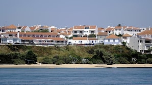 A coastal town with white buildings, a sandy beach, and a calm sea.