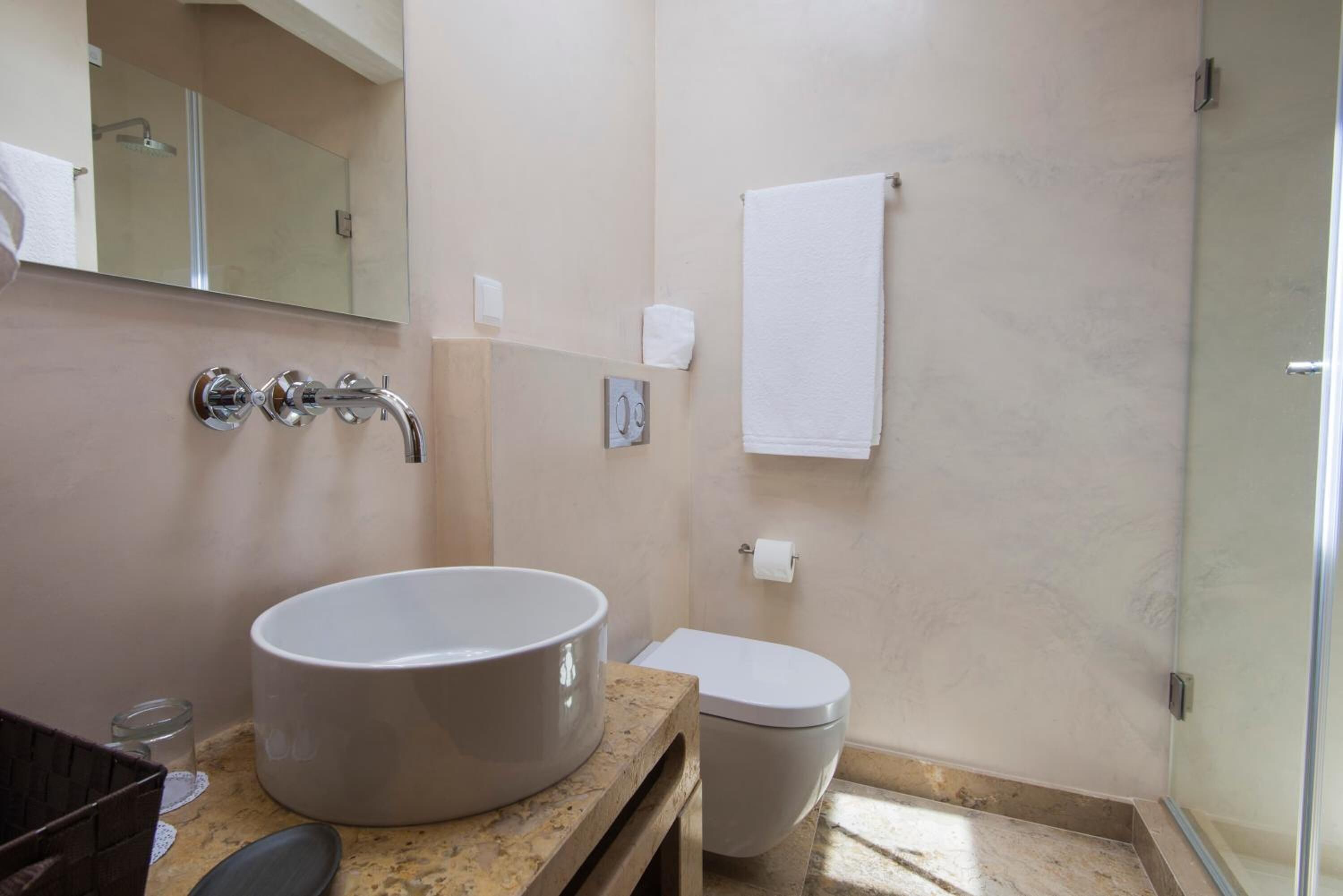 A bathroom with a large sink, toilet, and a glass shower enclosure.