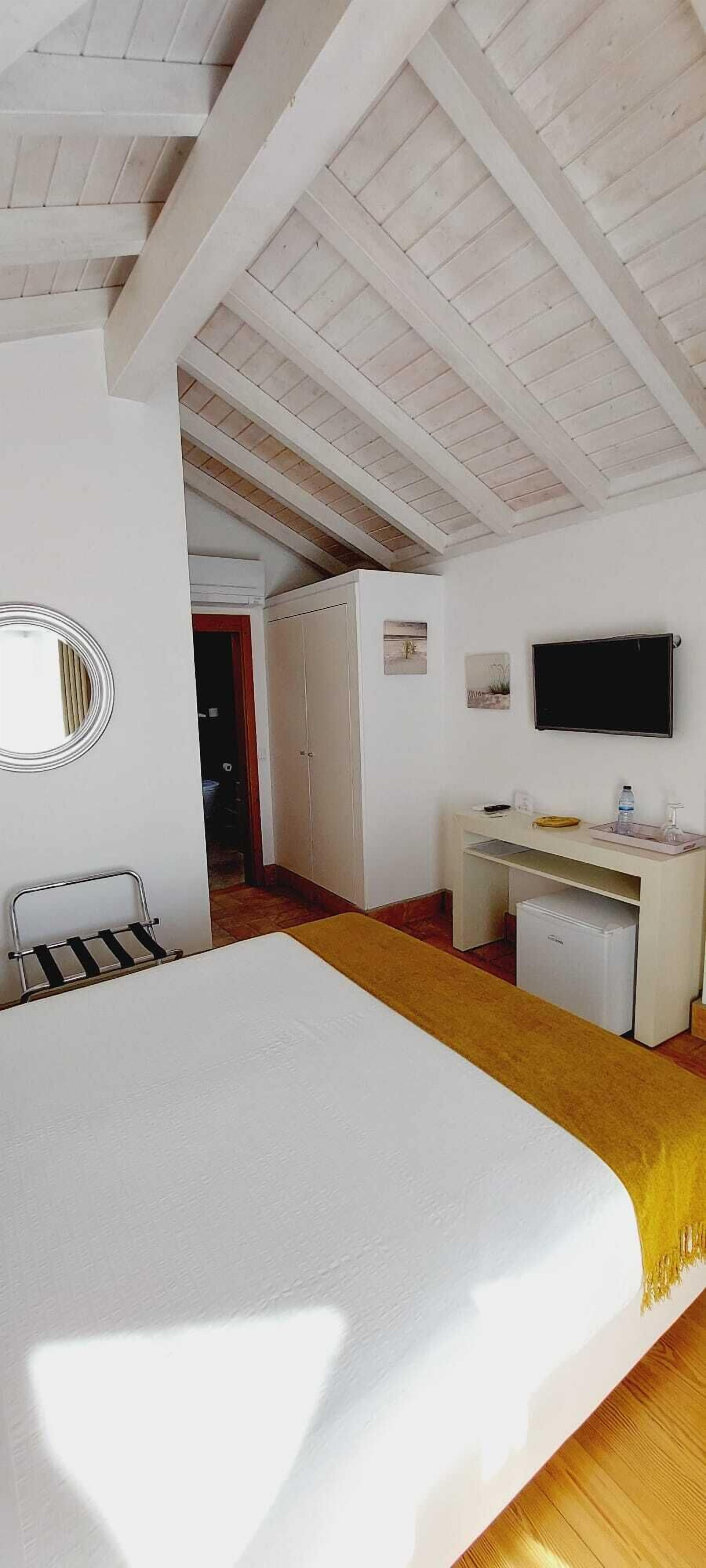 Een kamer met een bed, een bureau, een televisie en een kledingkast.