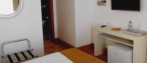 Een kamer met een bed, een bureau, een televisie en een kledingkast.