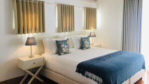 A bedroom with a bed, two nightstands, a lamp, and a window with curtains.