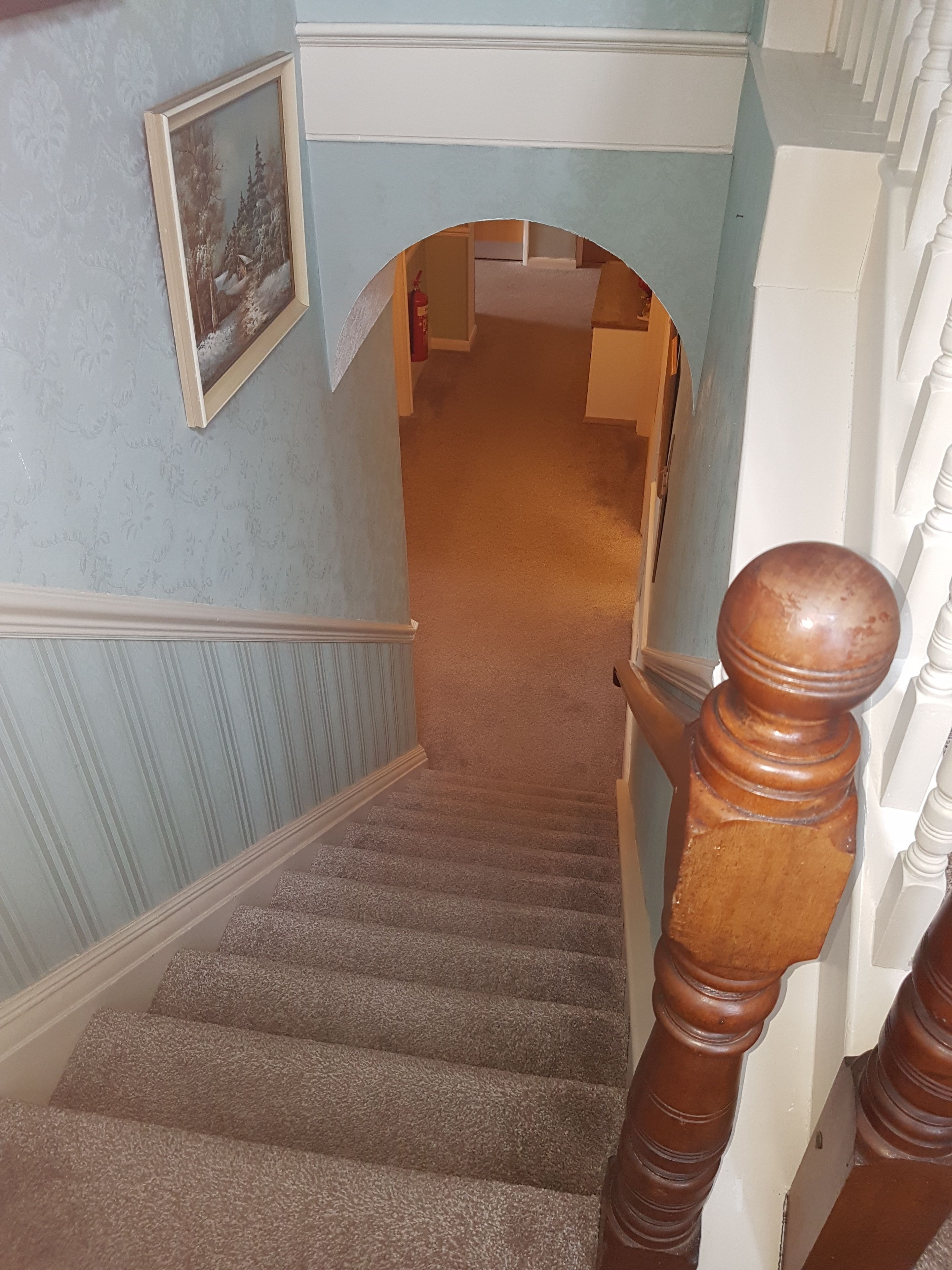 Un escalier avec une rampe en bois et un tableau accroché au mur.