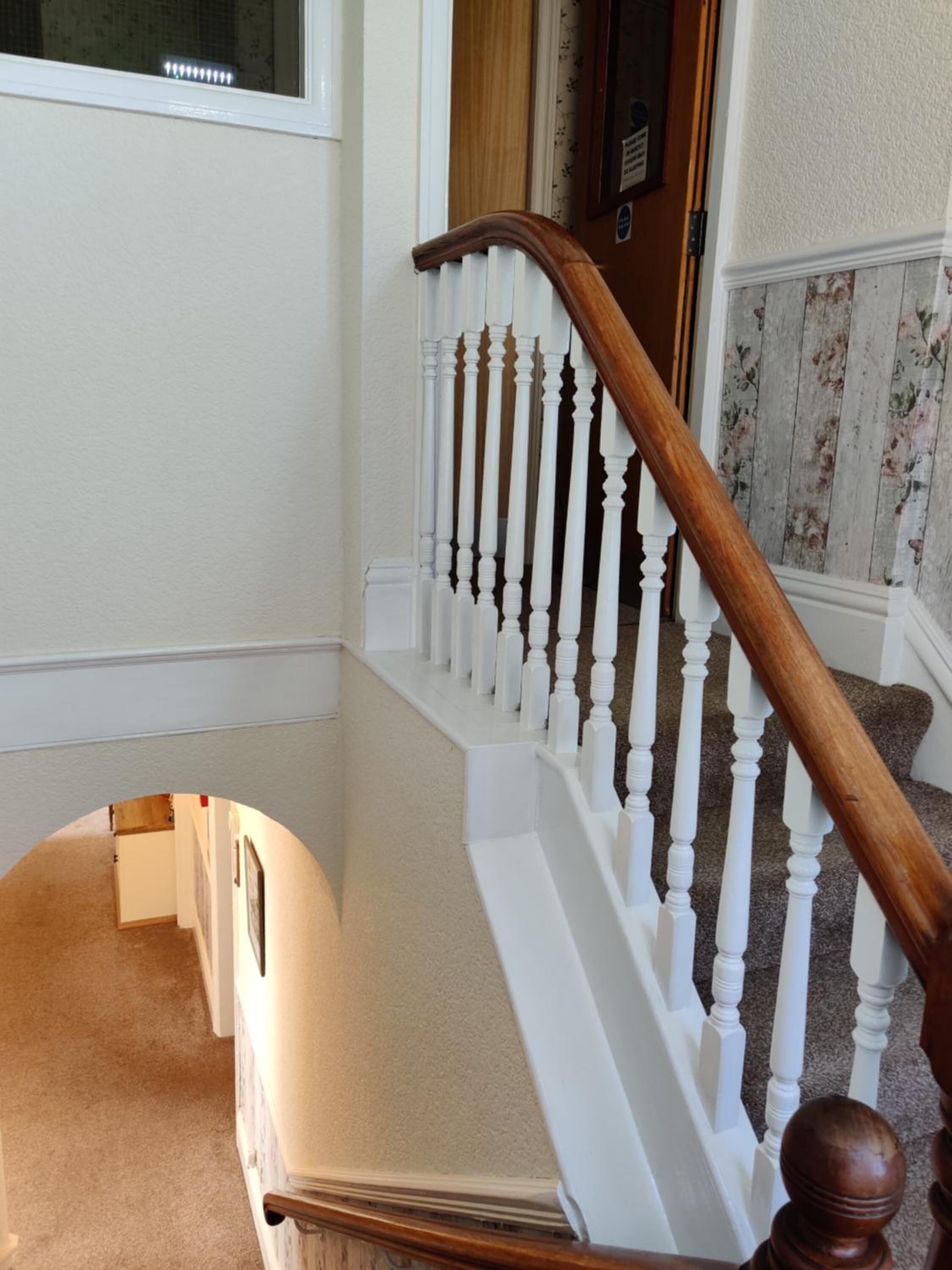 A staircase with white balusters and a wooden handrail.