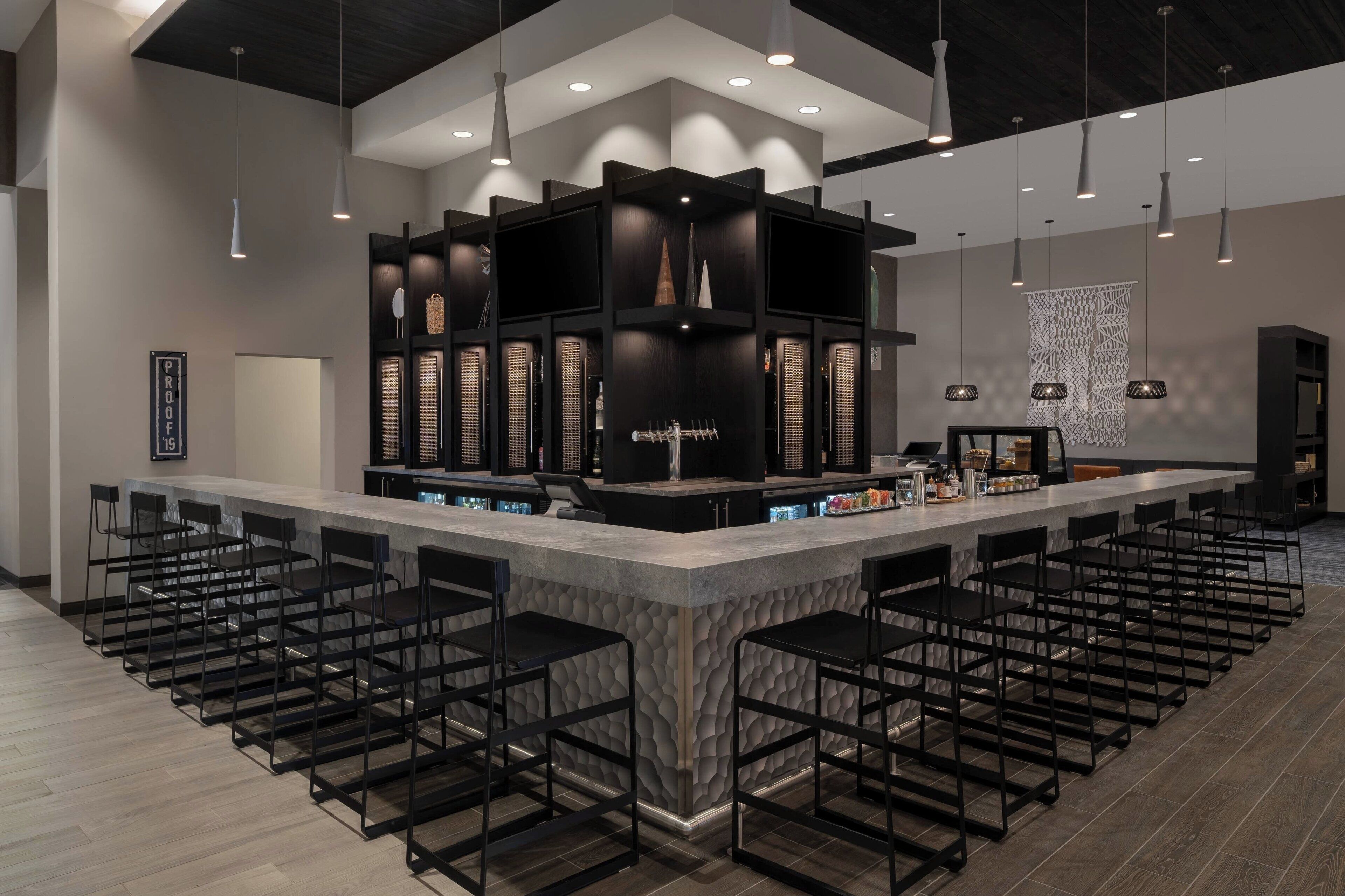 A modern bar area with a central counter, multiple bar stools, and pendant lighting.