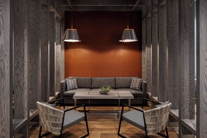 A modern interior with a sofa, two chairs, a table, and pendant lights.
