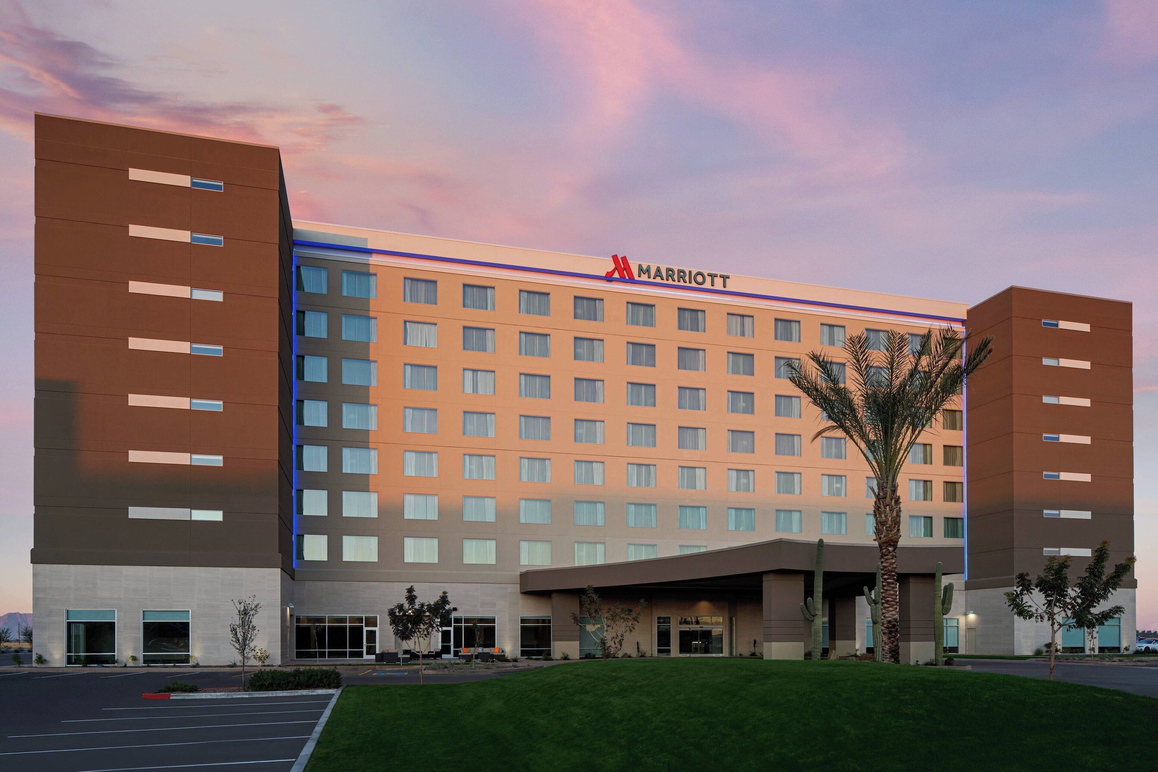 A Marriott hotel with a modern design, featuring a large parking lot and a well-maintained lawn.