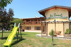 Un edificio con un cartel que dice "Ai Casali" y un patio de juegos con un tobogán amarillo.