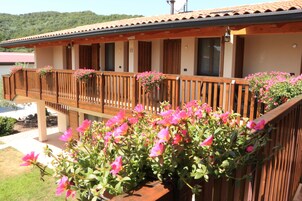 Un hotel con balcón de madera, jardineras de flores y vistas al lago.