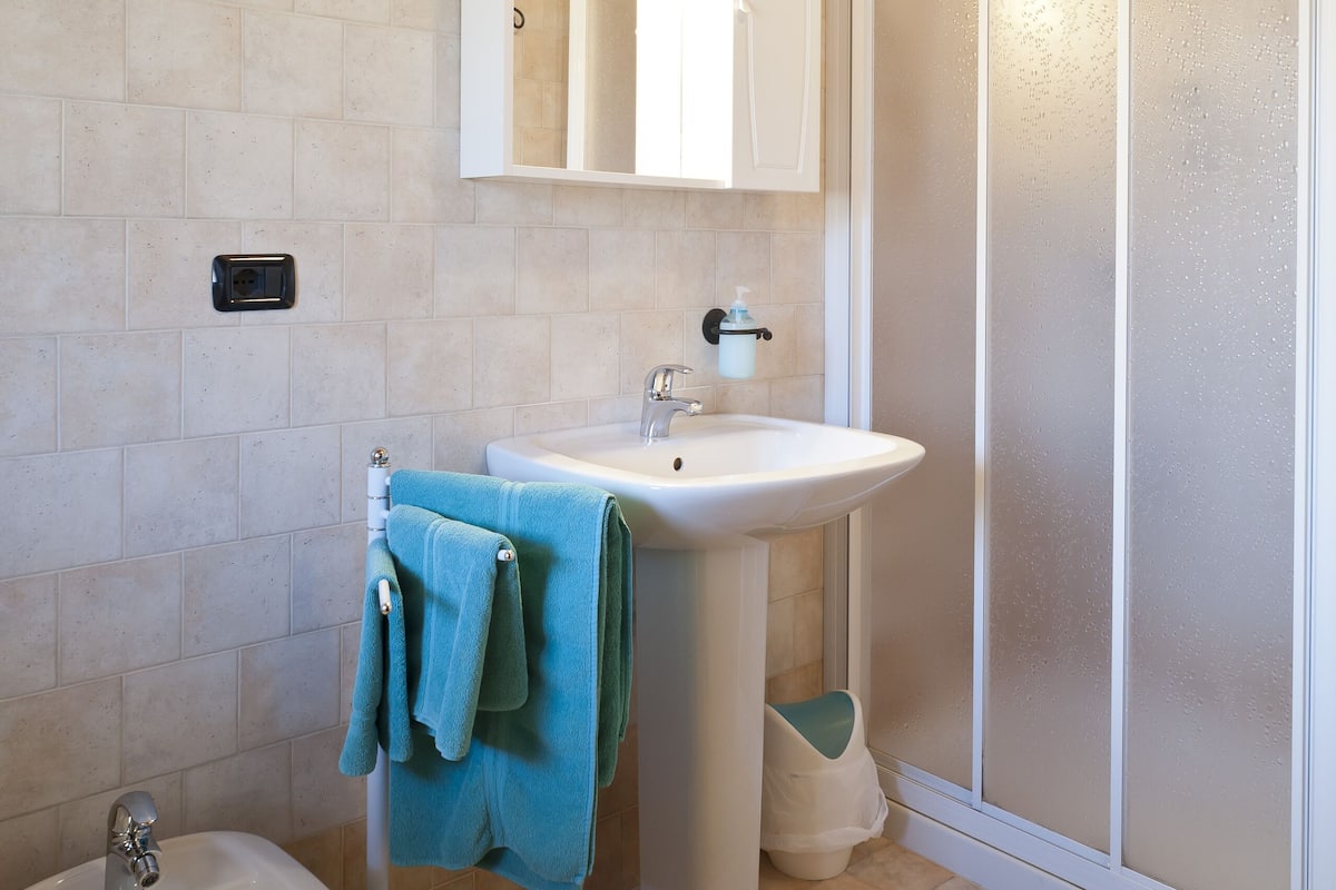 A bathroom with a sink, mirror, and shower.